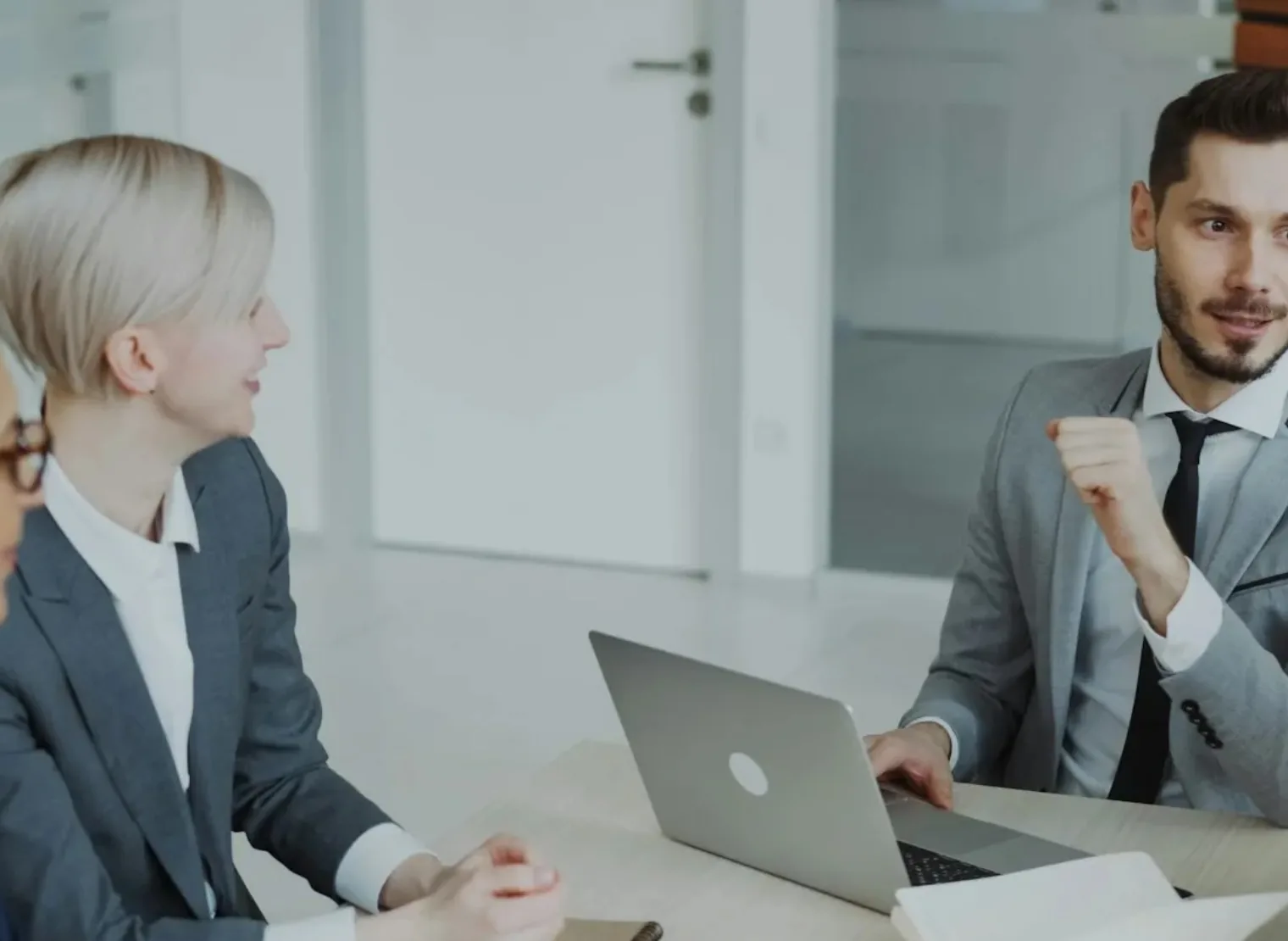 Duas pessoas conversam em frente a um notebook, em um escritório